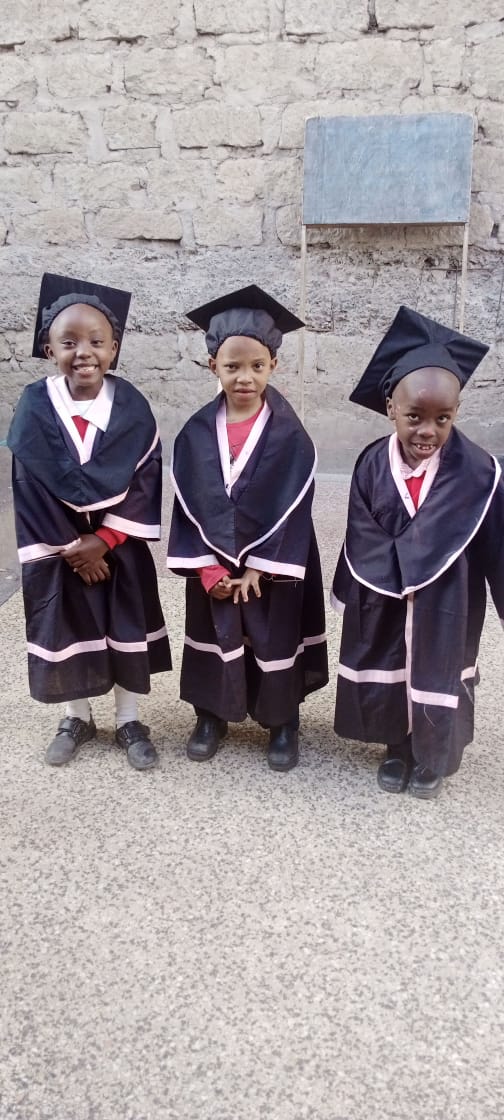 Three young children in graduation gowns and caps