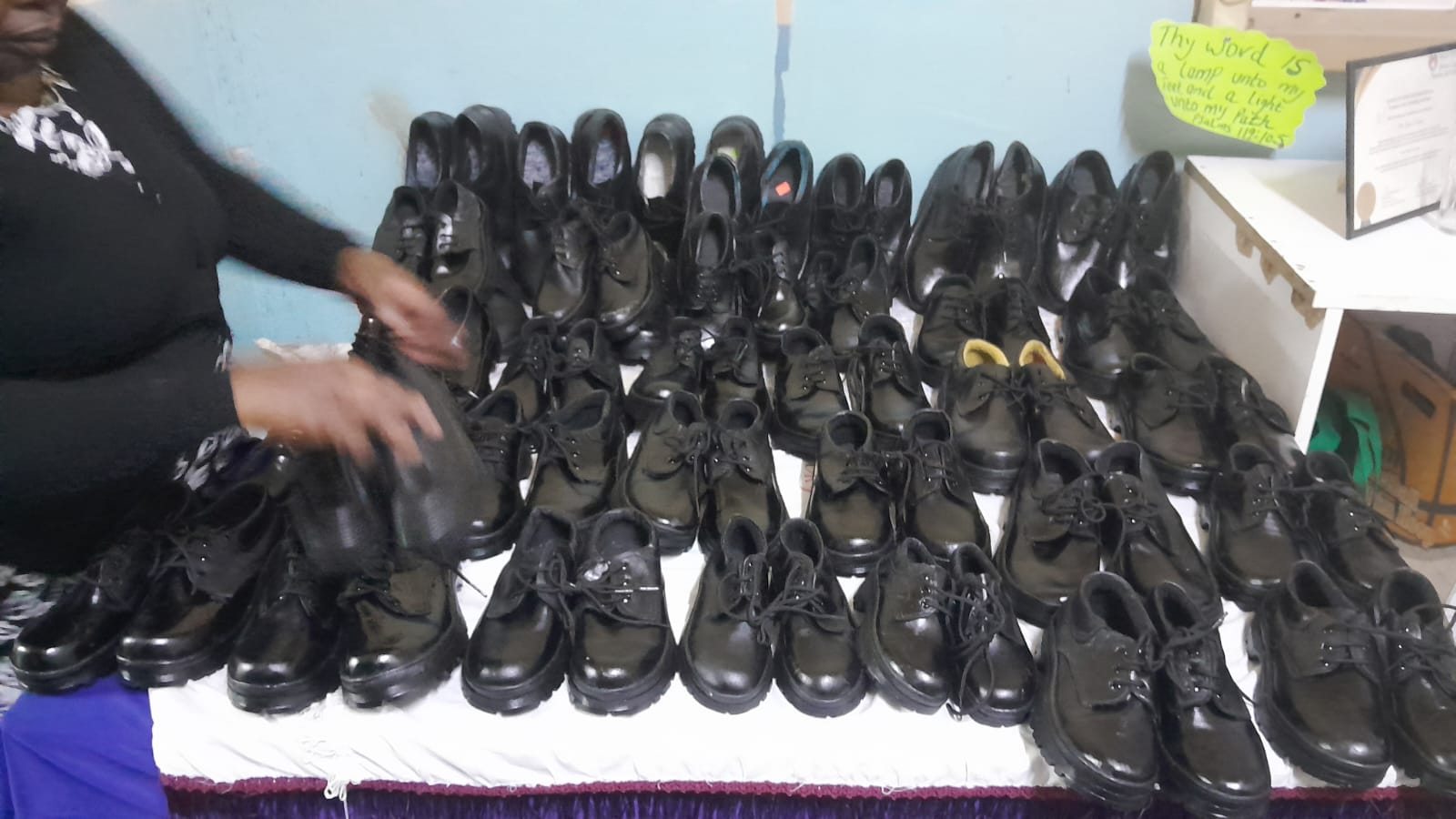 A member of staff beside rows of black school shoes