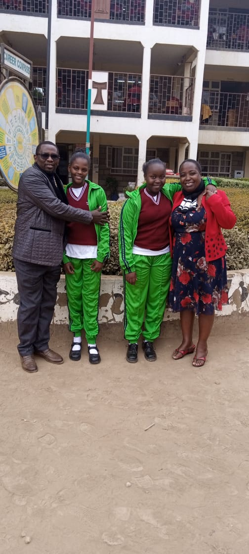 Two girls in school uniform with two of the home's directors