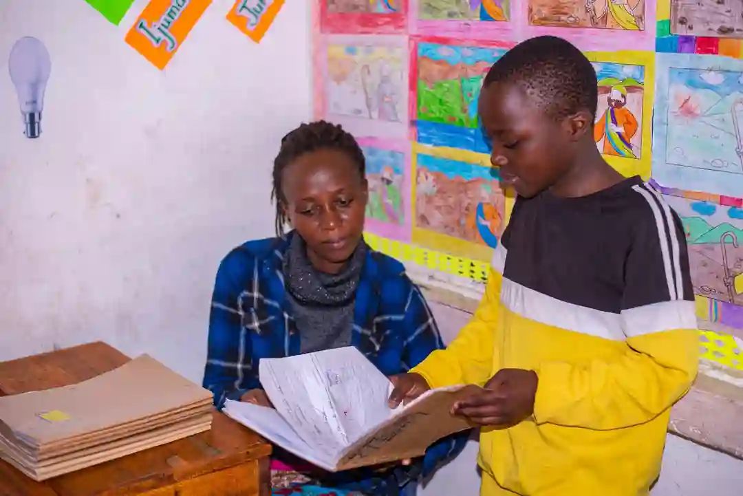 A volunteer helping a boy with his exercise books